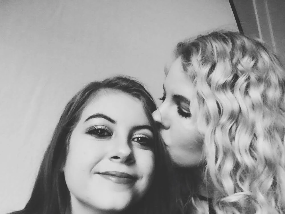 A black-and-white photo of one person kissing another on the forehead