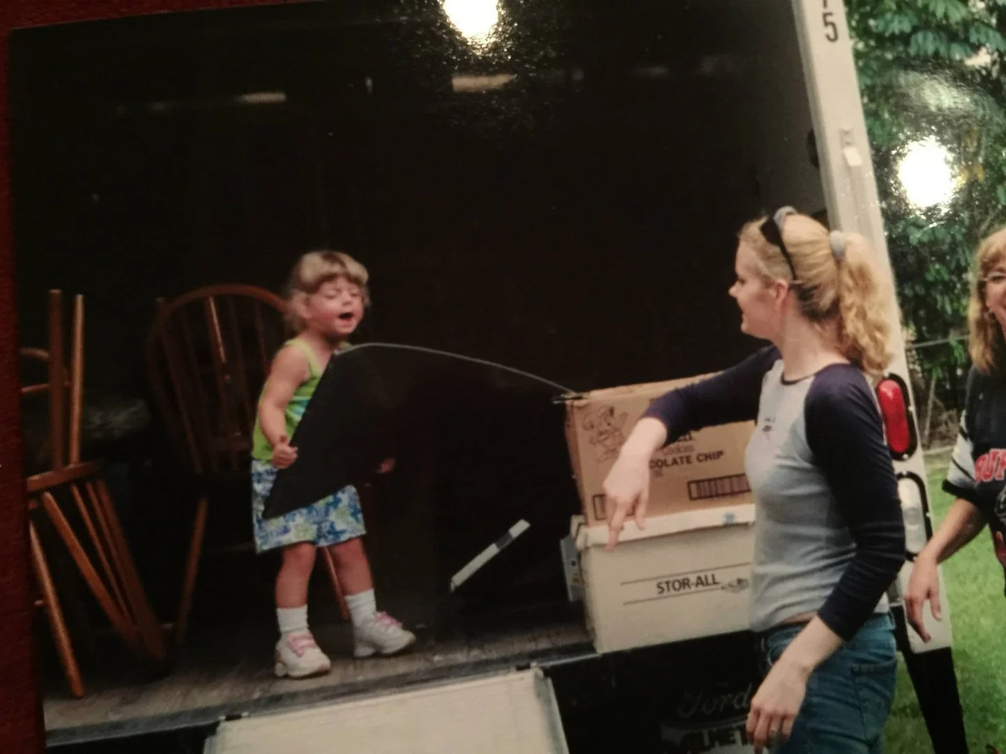 An older photograph of a child and adults beside a moving truck
