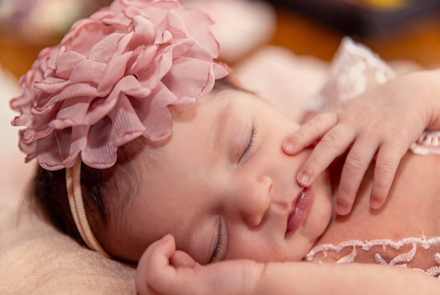 A sleeping newborn wearing a pink flower headband