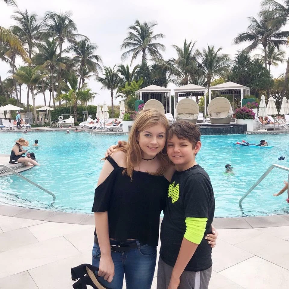 Two young people standing together beside a pool